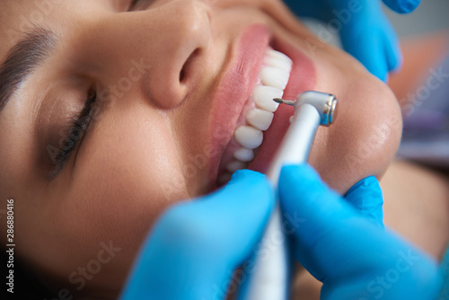 Charming young lady is receiving teeth treatment
