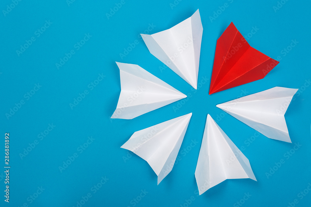Group of white paper plane in one direction and one red paper plane pointing in different way on blue background. Business for innovative Group of white paper plane in one direction and one red paper plane pointing in different way on blue background. Business for innovative