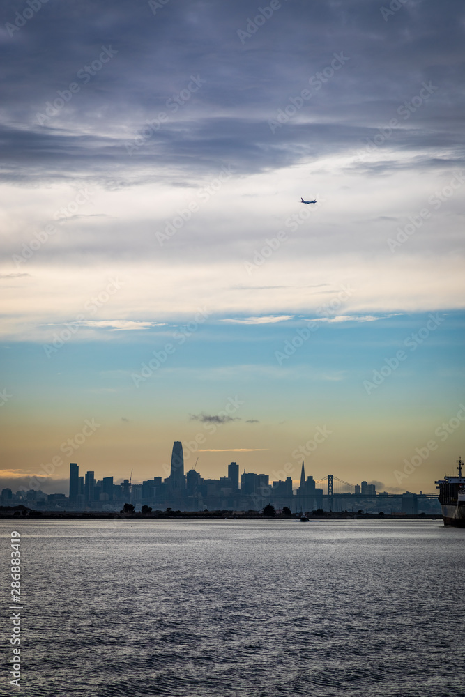 Plane flying over San Francisco skyline close to sunset