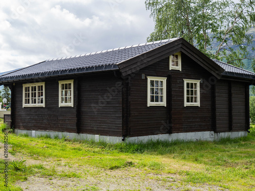 Traditional Brown Wooden Scandinavian House with White Windows at a Camping on the green lawn