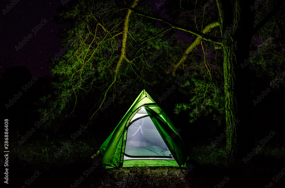 Green tent in the forest at night. Camping with a tent in the forest Green tent in the forest at night. Camping with a tent in the forest