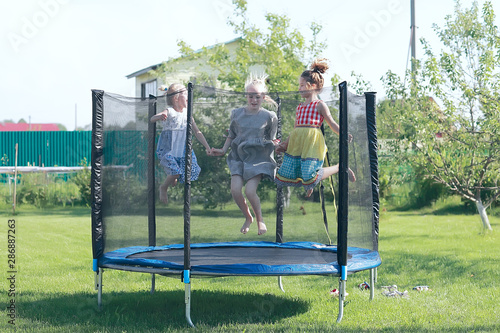 children jumping on a trampoline, girlfriends having fun in the summer in a recreation park on a trampoline photo