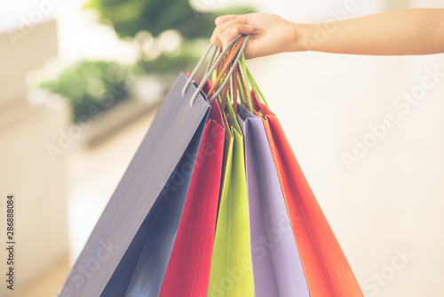 Close up photo of human hand holding colorful shopping bags