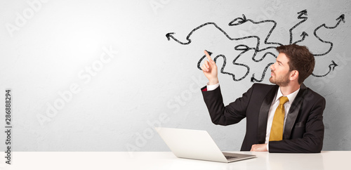 Businessman sitting at desk with direction concept