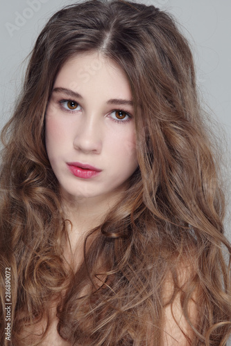 Portrait of young beautiful girl with clean makeup and long curly hair