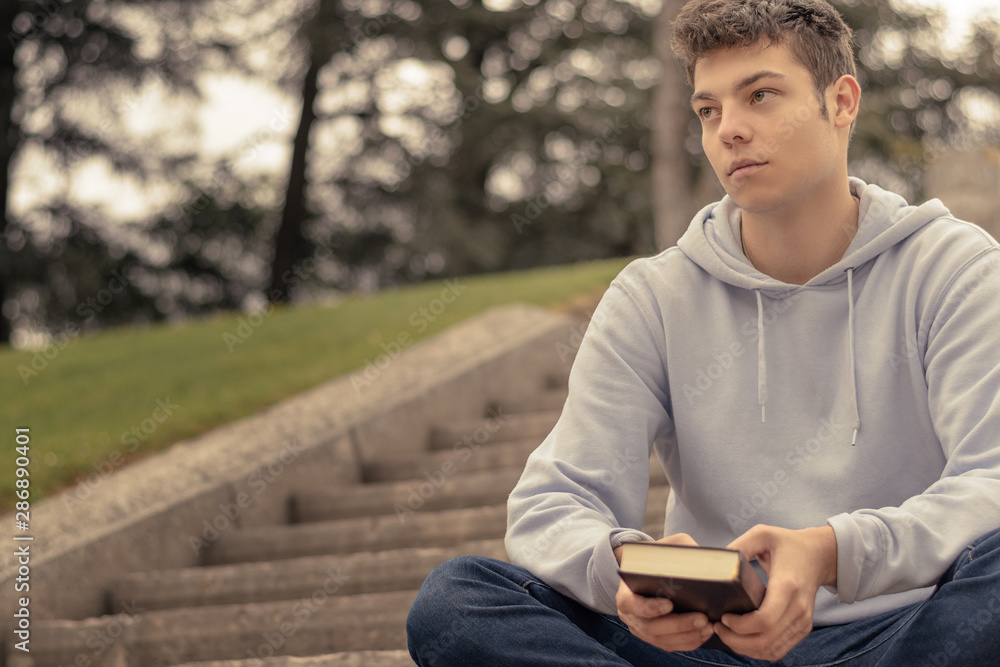 Christian worship and praise. A young man is praying and reading the bible in the evening. Christian worship and praise. A young man is praying and reading the bible in the evening.