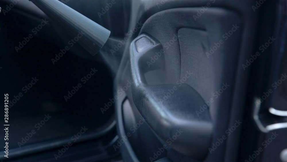 Car service. Worker washing of interior by a special cleaners under pressure.