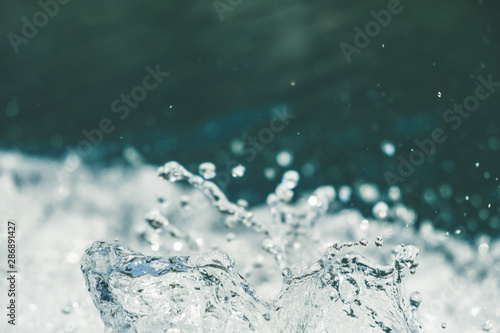 Splash of fresh water with drops caught in the air with turquoise river surface in the background  