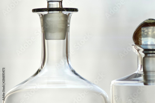 part of two transparent bottles of spirits whiskey gin alcohol white background