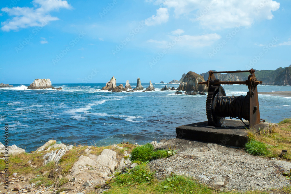 Tow winch in front of the geological formations of the wild beach of la gueirúa.