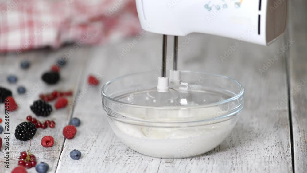 Woman preparing whipped cream in kitchen. Woman preparing whipped cream in kitchen.