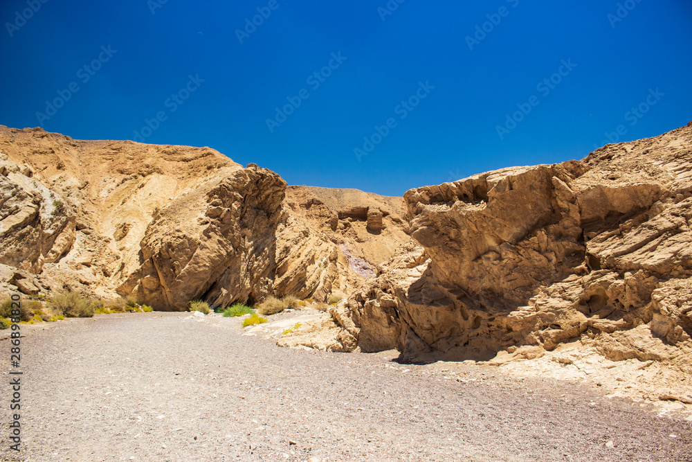 Israeli desert canyon entrance with dry ground and small sharp rocky stones path way Middle East travel destination