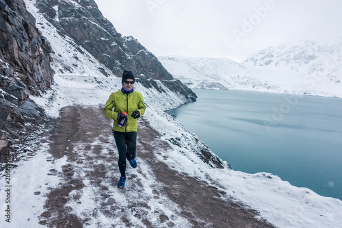 Woman running on an icy road near a reservoir during winter. 