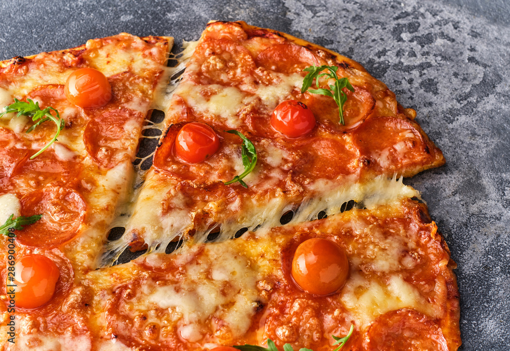 Slice of pepperoni pizza with cherry tomatoes. Sliced tasty pepperoni pizza on the grey stone background. Top view Slice of pepperoni pizza with cherry tomatoes. Sliced tasty pepperoni pizza on the grey stone background. Top view