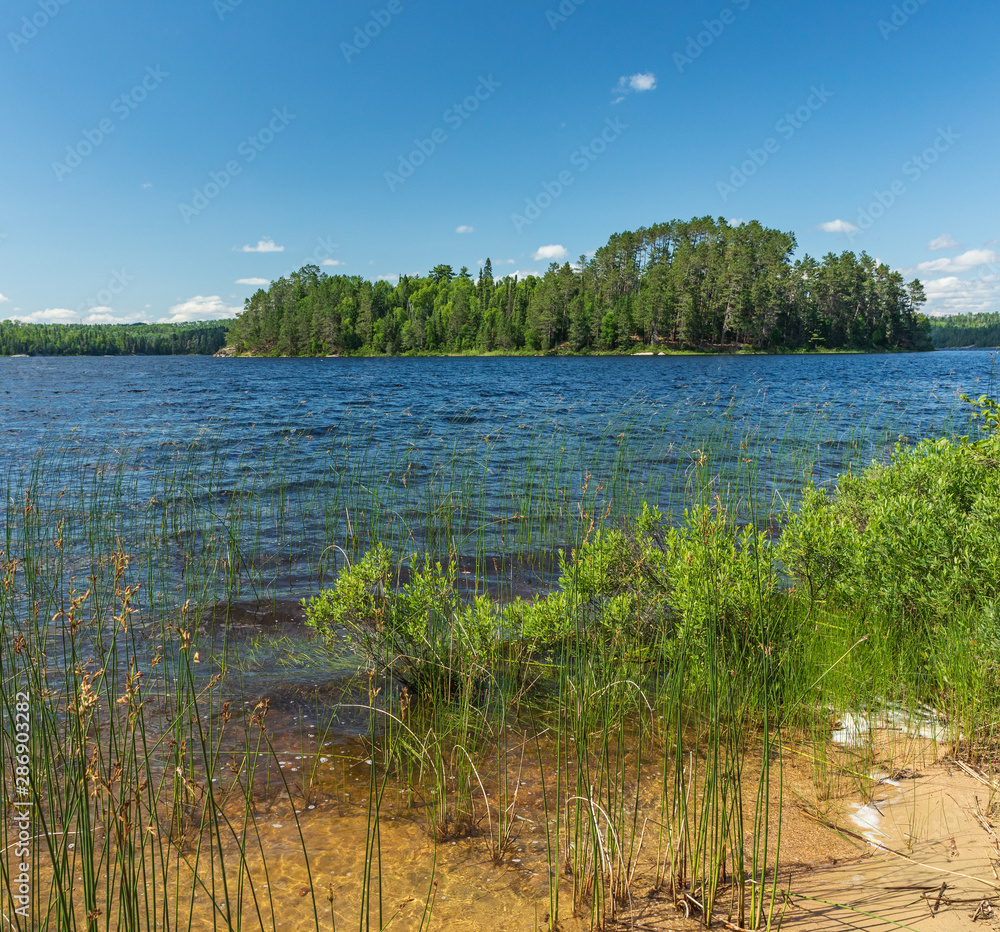 View of an Island on French Lake from a sandy beach portage entry point at the Chippewa campground in Quetico Provincial Park, Atikokan, Ontario, Canada