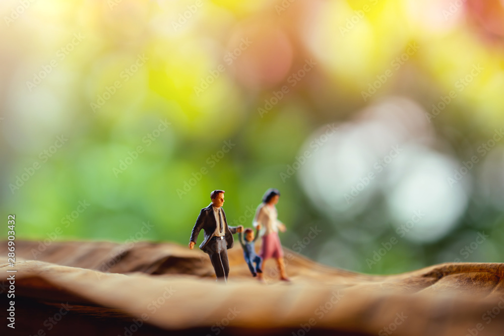 Love and Happy Family. Work Life Balance Concept. Miniature of Father, Mother and Son holding Hands and Walking on Dry Leaf in Park