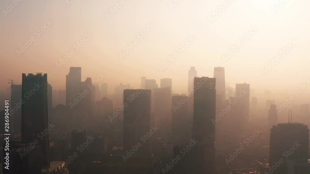 JAKARTA, Indonesia - August 27, 2019: Aerial view of silhouette of office building with dense air pollution smoke in business district. Shot in 4k resolution from a drone flying upwards JAKARTA, Indonesia - August 27, 2019: Aerial view of silhouette of office building with dense air pollution smoke in business district. Shot in 4k resolution from a drone flying upwards