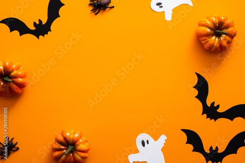 Happy halloween holiday concept. Halloween decorations, pumpkins, bats, ghosts, on orange background. Halloween party greeting card mockup with copy space. Flat lay, top view, overhead.