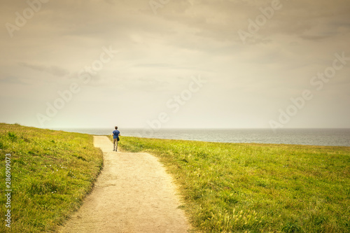 man walking on a lonely path to the horizon to reach his goal