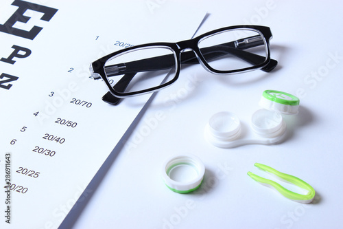 glasses and lenses for vision correction and a table for checking vision on a light background.