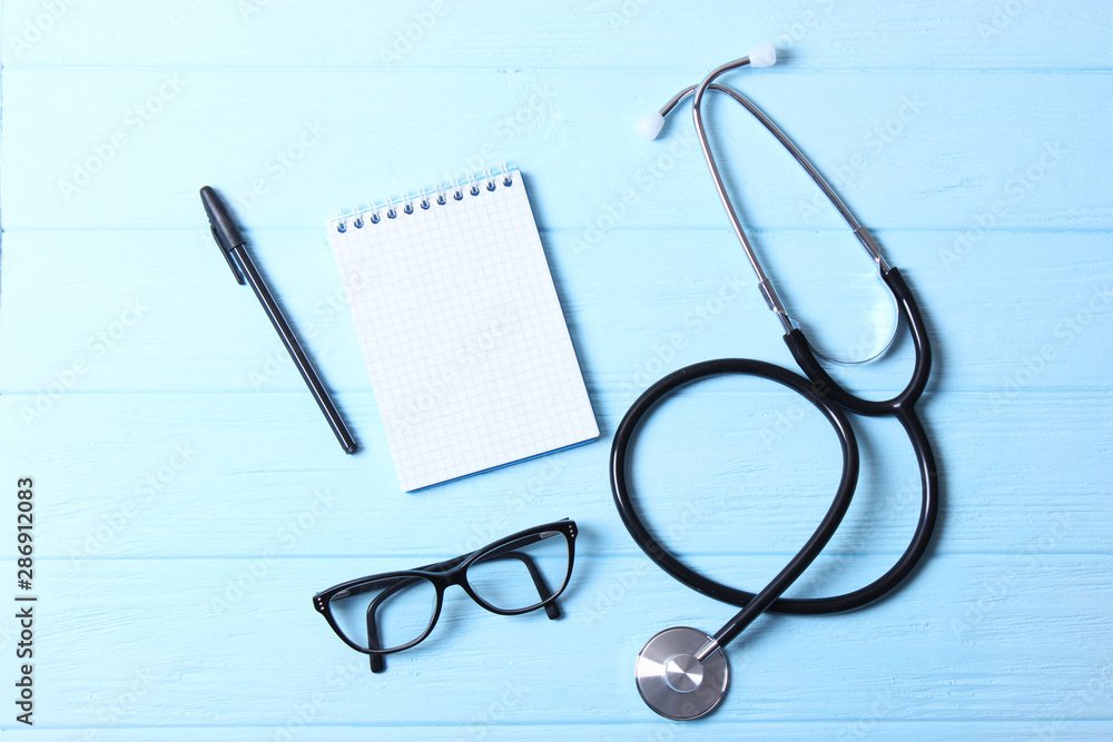 Doctor's desk top view. Stethoscope, pills, glasses and notebook on a colored background. Doctor's desk top view. Stethoscope, pills, glasses and notebook on a colored background.