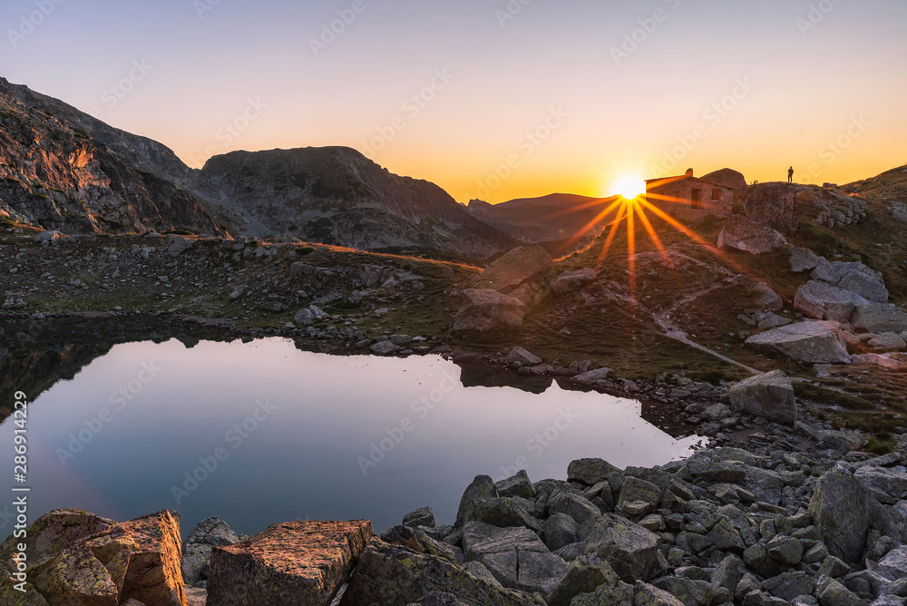 Amazing landscape of The Scary lake during warm summer sunset with small stone shelter, Rila mountain national park, Bulgaria