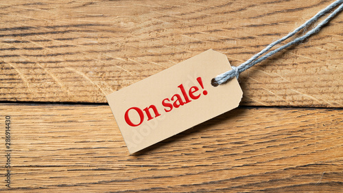 Hangtag with the message "on sale" on wooden background