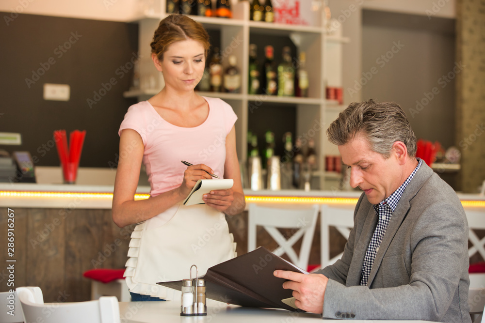 Young waitress taking order from mature customer at restaurant Young waitress taking order from mature customer at restaurant