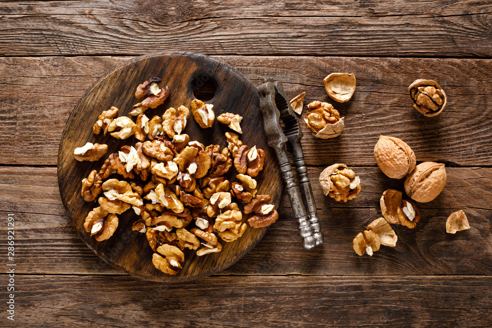 Fototapeta premium Walnuts. Kernels and whole nuts on wooden rustic table, top view