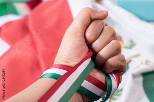Woman hand holding hard a ribbon with the colors of mexican flag. Mexican Independence Day celebration
