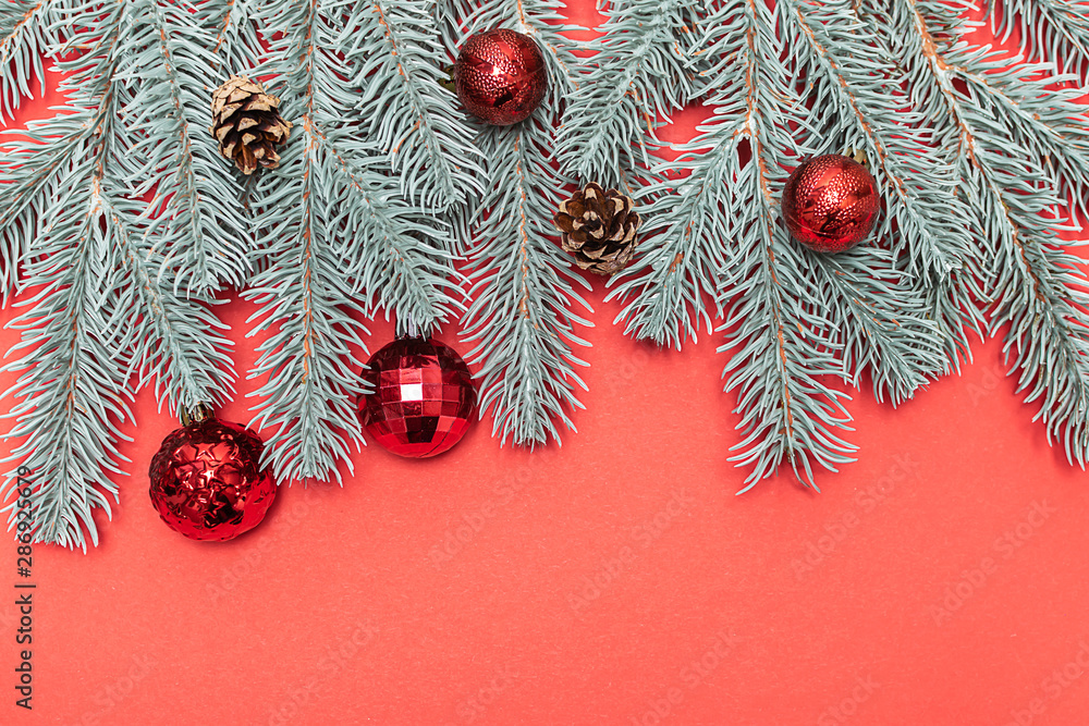 Creative flat lay overhead Christmas composition with fir tree branches, cones and bright ballsvon red background with copy space for your text Minimalism style composition. Creative flat lay overhead Christmas composition with fir tree branches, cones and bright ballsvon red background with copy space for your text Minimalism style composition.