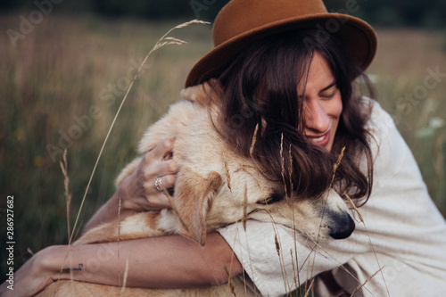 Beautiful young woman relaxed and carefree enjoying a summer sunset with her lovely dog photo