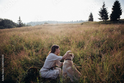 Girl and her friend dog are playing on the straw field background. Beautiful young woman relaxed and carefree enjoying a summer sunset with her lovely dog © gartmanart