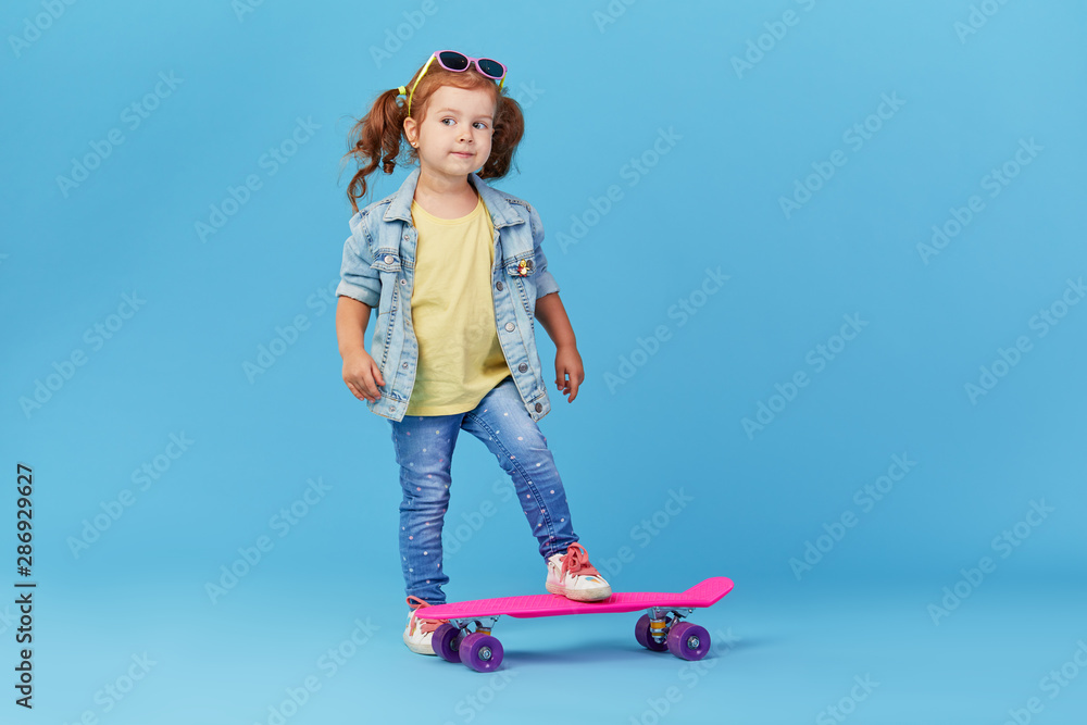 Stylish cool little girl child with skateboard over blue background Stylish cool little girl child with skateboard over blue background
