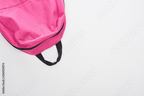 Top view of bright pink school bag isolated on white