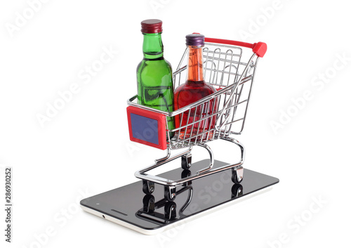 Metal cart whit bottle from store and smartphone on a white background photo