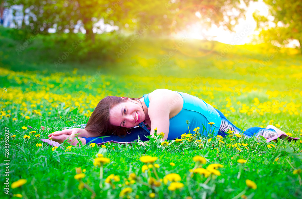 Smiling brunette woman stretching outdoor on the grass Smiling brunette woman stretching outdoor on the grass