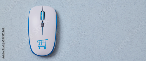 Online shopping, buying and e-commerce. Computer mouse with cymbol of basket. Blue background photo