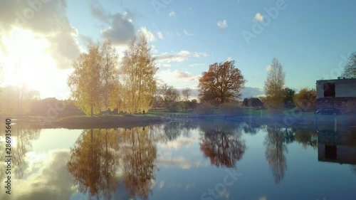 Aerial shot of young men walking towards the bridgeon a countryside lake - sun shining through the trees, partly in lense making beautiful sun flare photo