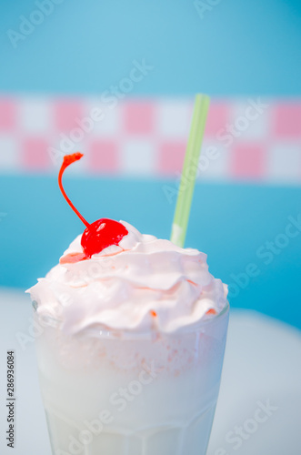 Glass of milkshake with whipped cream and cherry