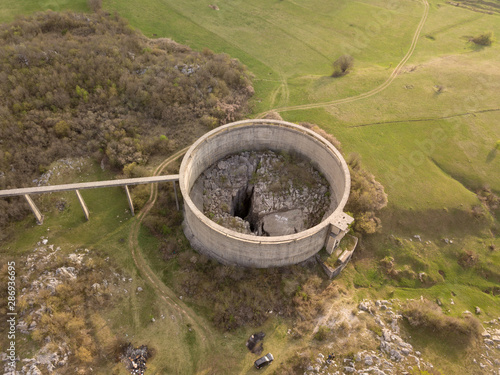 Slivski ponor is a ponor or a sinkhole with a huge shaft on Niksicko polje close to Niksici in Montenegro. A circular dam that is preventing outflow of water from the polje surrounds the cave.  photo