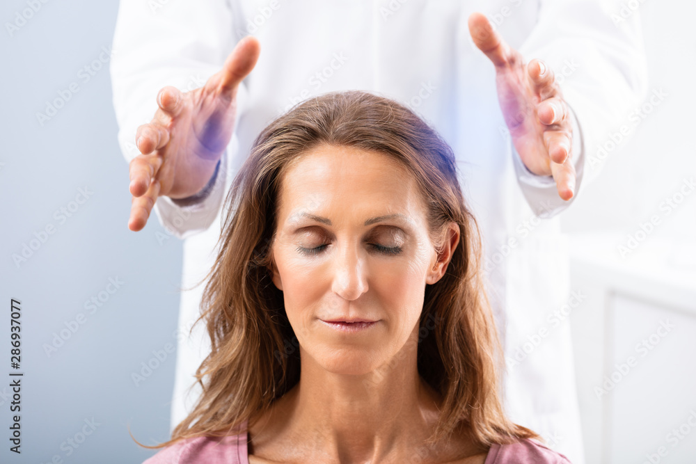 Fototapeta premium Therapist Giving Reiki Healing Treatment To Woman