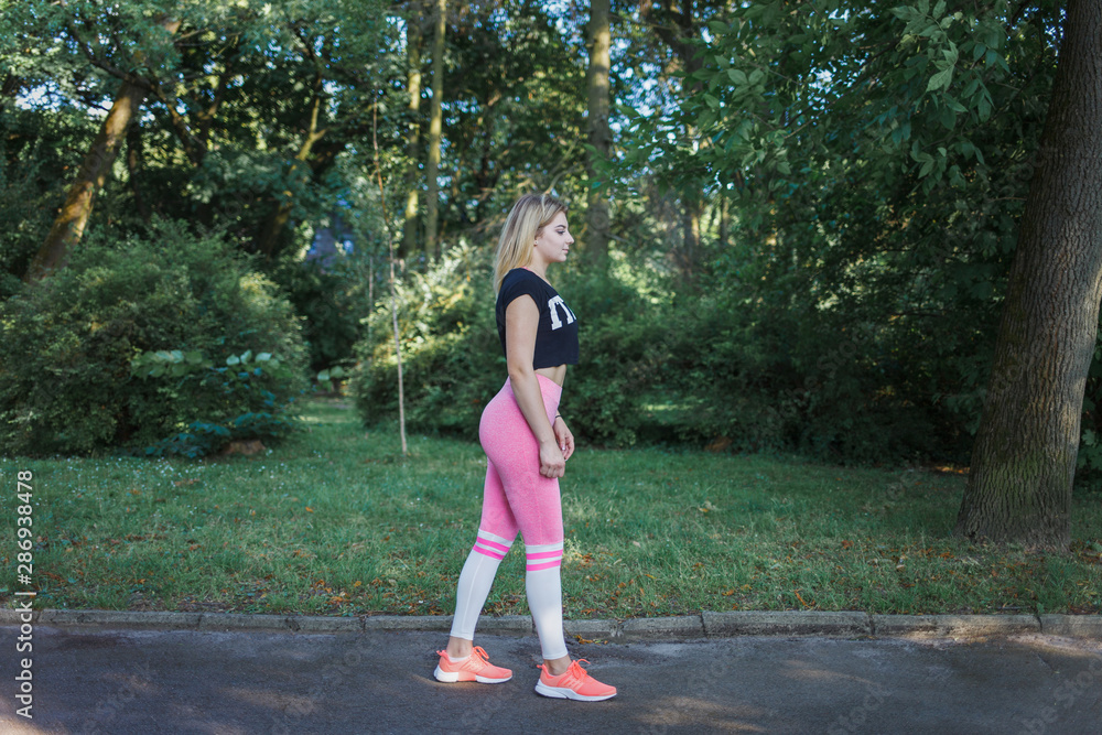 Side view of fit young woman in sportswear getting ready for workout. Healthy woman in park Side view of fit young woman in sportswear getting ready for workout. Healthy woman in park