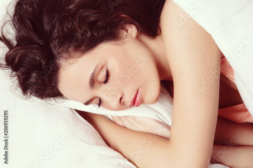 Young beautiful woman with curly hair sleeping in bed