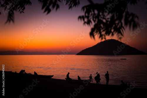 Lake Malawi at Monkey Bay, People gathering togehter at the Beach, washing dishes, talking, red sunset, South-East-Africa