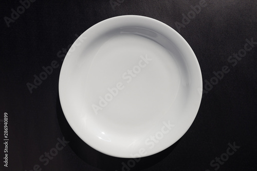 White ceramic round plate on black background