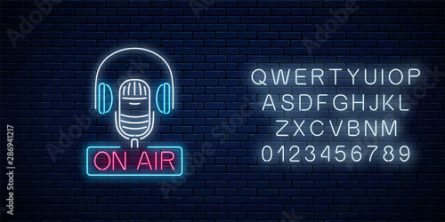 Neon on the air sign with microphone and headphones with alphabet. Glowing signboard of radio station.