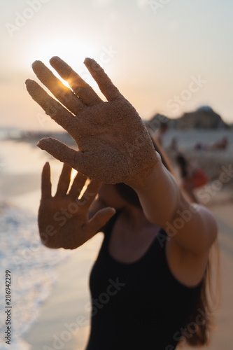 silhouette of woman and female sandy hands at sunset. sun shines through hand. concept of life, travel, healthy lifestyle, holiday, vacation.