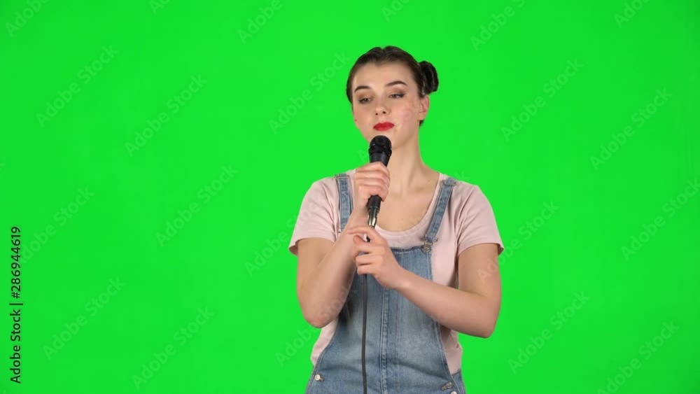 Attractive girl sings into a microphone and moves to the beat of music Attractive girl sings into a microphone and moves to the beat of music