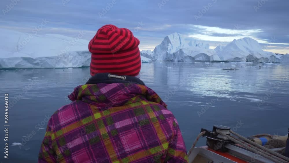 Rear view of tourist on boat enjoying iceberg view at Disko Bay against sky Rear view of tourist on boat enjoying iceberg view at Disko Bay against sky